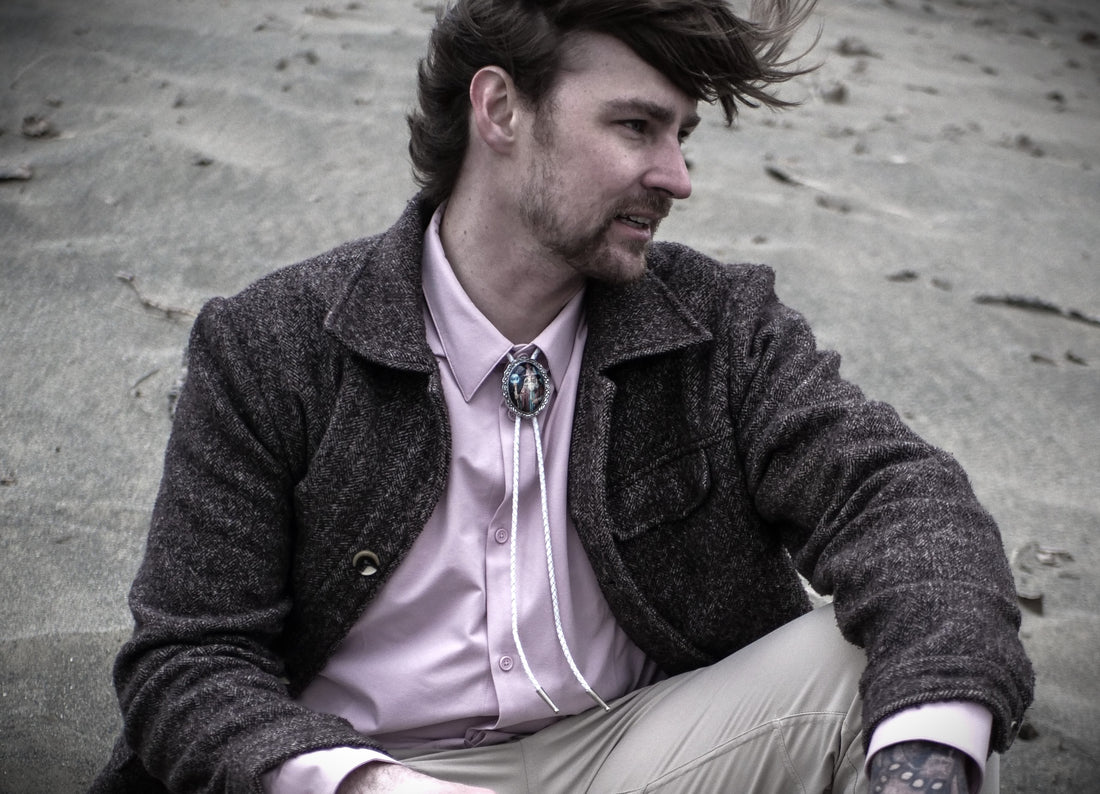 A man with punk hair style wearing a white bolo tie