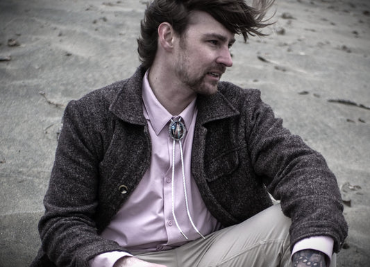 A man with punk hair style wearing a white bolo tie