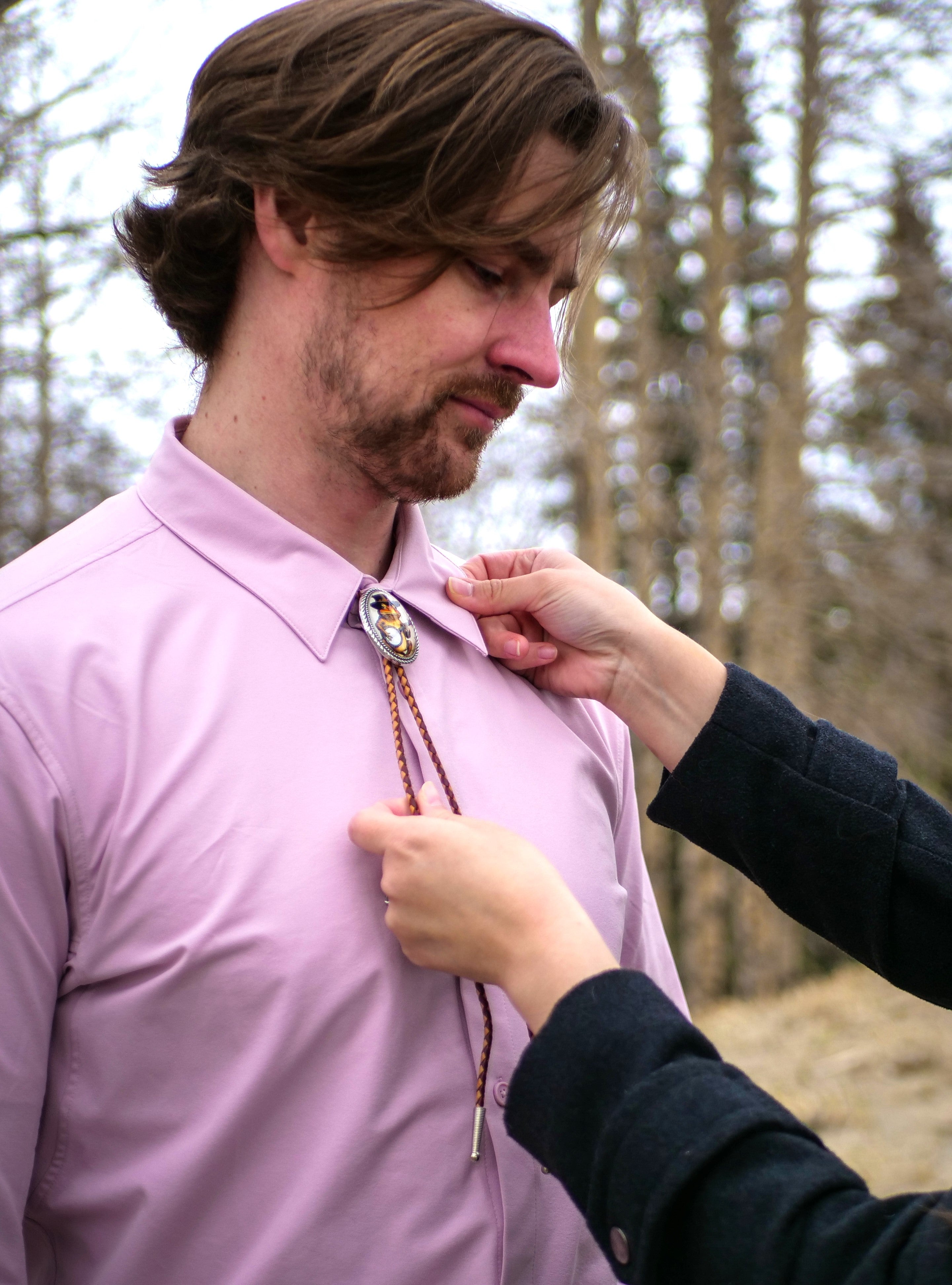a woman adjusts a bola necktie on her husband's shirt collar