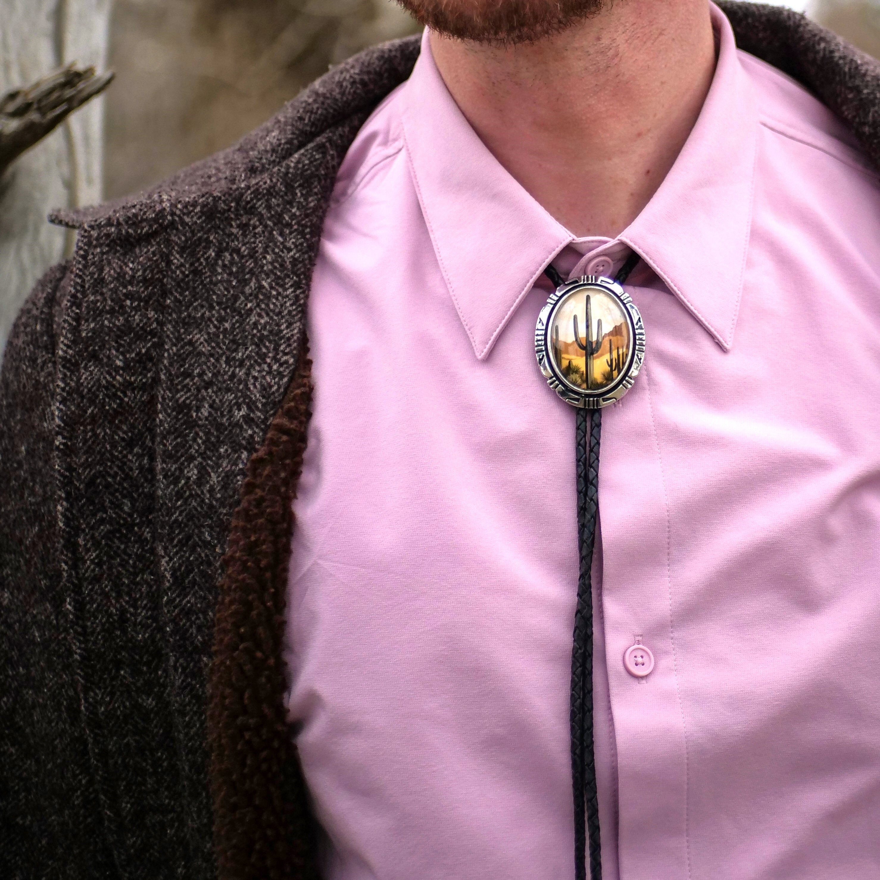 a mand wearing saguaro cactus cowboy bolo tie with a pink shirt and peacoat