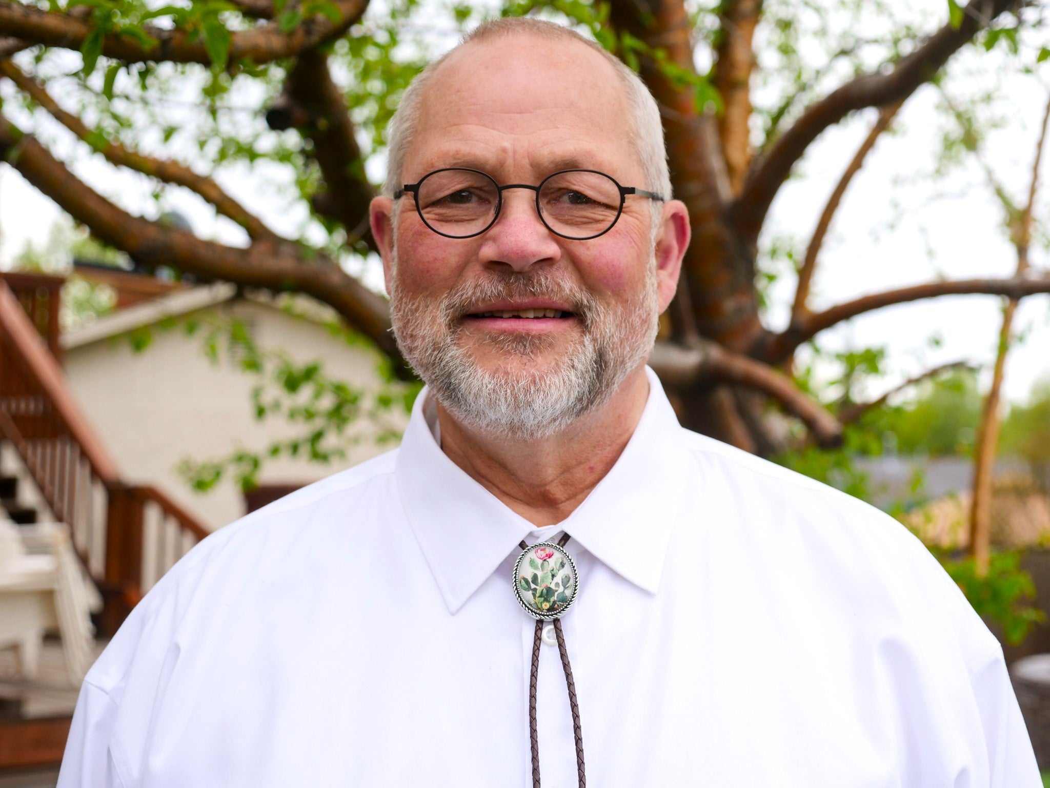 A smiling man is western a western bolo tie